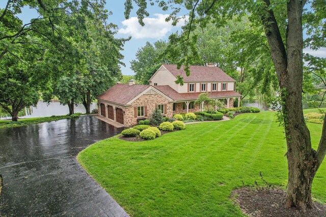 7316 Gleneagle Cir, Lakewood, IL 60014 - view of front of house with an attached garage, a chimney, driveway, a front lawn, and brick siding