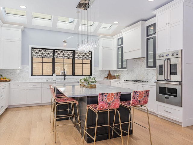 527 N Ellsworth St, Naperville, IL 60563 - kitchen with stainless steel double oven, light wood-style flooring, a sink, white cabinets, and recessed lighting