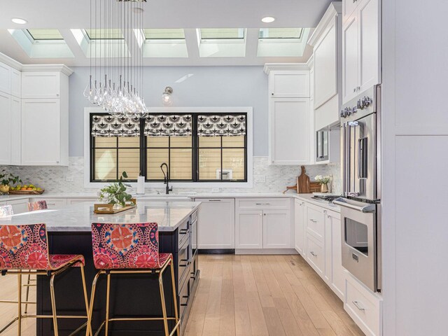 527 N Ellsworth St, Naperville, IL 60563 - kitchen featuring a skylight, white cabinetry, light wood-type flooring, light stone counters, and recessed lighting