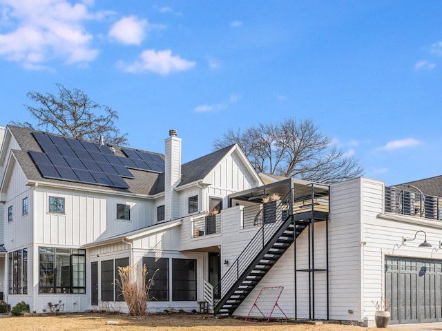 527 N Ellsworth St, Naperville, IL 60563 - rear view of property featuring board and batten siding, a sunroom, roof mounted solar panels, stairway, and a chimney