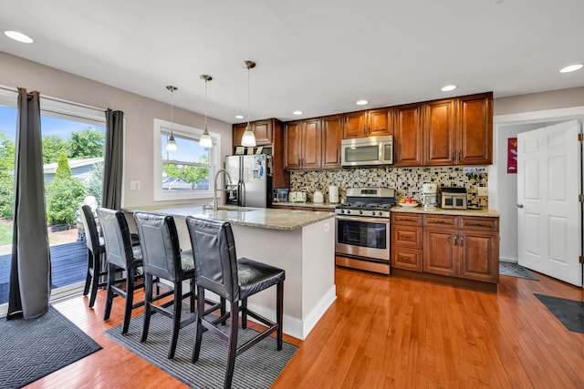 127 Saint Joseph Ave, Joliet, IL 60436 - kitchen with stainless steel appliances, a sink, light wood-style flooring, decorative backsplash, and a breakfast bar