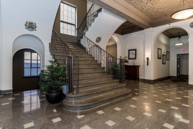 212 N Center St Unit 502, Bloomington, IL 61701 - staircase featuring granite tiled floors, a towering ceiling, baseboards, ornamental molding, and arched walkways