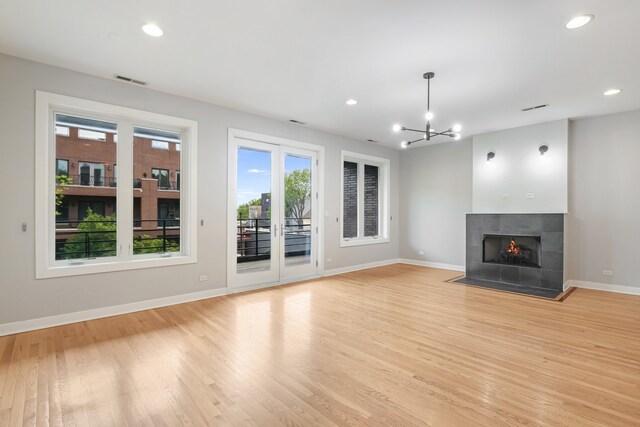 828 N California Ave Unit 3, Chicago, IL 60622 - unfurnished living room featuring baseboards, light wood finished floors, a tiled fireplace, recessed lighting, and a chandelier