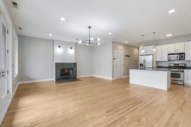 828 N California Ave Unit 3, Chicago, IL 60622 - unfurnished living room with recessed lighting, baseboards, light wood-style flooring, a tiled fireplace, and a chandelier