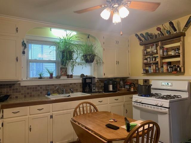 1013 Guion St, Ottawa, IL 61350 - kitchen featuring white range with gas cooktop, a sink, a ceiling fan, and white cabinetry