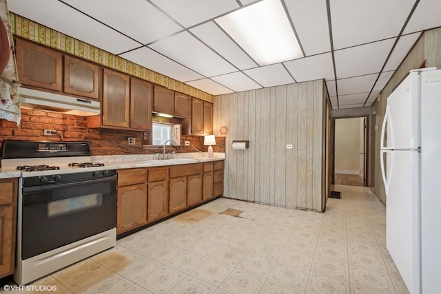 2630 N Austin Ave, Chicago, IL 60639 - kitchen with range with gas cooktop, freestanding refrigerator, under cabinet range hood, a sink, and a drop ceiling