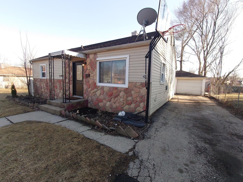 1139 E Galena Blvd, Aurora, IL 60505 - view of front facade featuring stone siding, an outdoor structure, a detached garage, and asphalt driveway