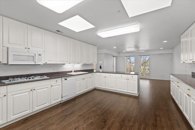 380 Green Bay Rd Unit 4D, Winnetka, IL 60093 - kitchen featuring white appliances, a skylight, a peninsula, dark wood-style floors, and dark countertops
