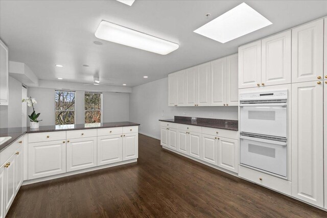 380 Green Bay Rd Unit 4D, Winnetka, IL 60093 - kitchen with double oven, a skylight, dark wood-style floors, white cabinetry, and recessed lighting