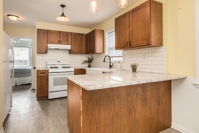 6136 N Nagle Ave, Chicago, IL 60646 - kitchen with white appliances, under cabinet range hood, a peninsula, a sink, and plenty of natural light