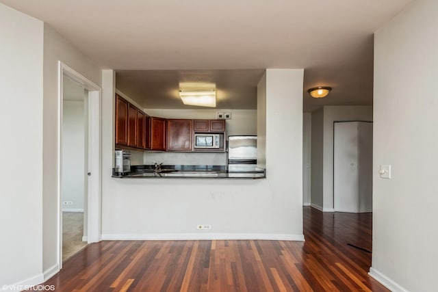525 W Hawthorne Pl Unit 2701, Chicago, IL 60657 - kitchen with stainless steel microwave, dark countertops, dark wood-style floors, and baseboards