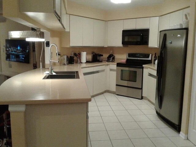 121 Chatsworth Cir, Schaumburg, IL 60194 - kitchen with black microwave, stainless steel range with electric cooktop, freestanding refrigerator, a peninsula, and a sink