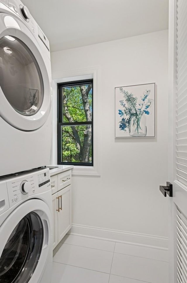 4102 W Eddy St, Chicago, IL 60641 - laundry room featuring stacked washer / dryer, cabinet space, light tile patterned floors, and baseboards