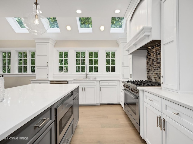 1360 Turvey Rd, Downers Grove, IL 60515 - kitchen featuring a skylight, stainless steel appliances, white cabinets, light countertops, and hanging light fixtures