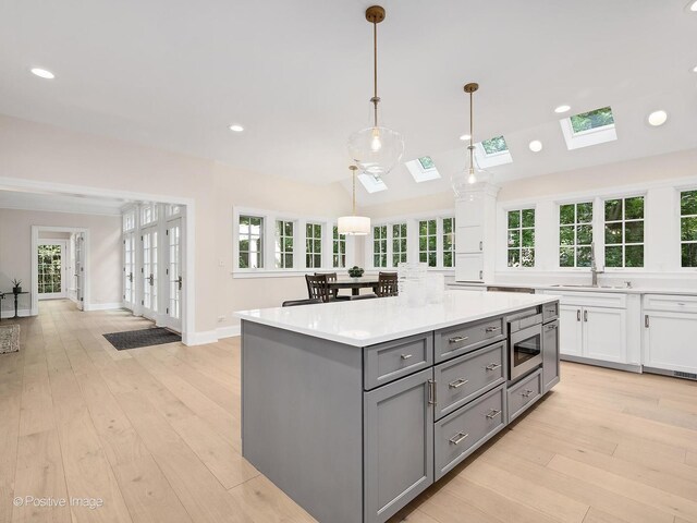 1360 Turvey Rd, Downers Grove, IL 60515 - kitchen with gray cabinetry, stainless steel microwave, white cabinetry, a skylight, and light countertops