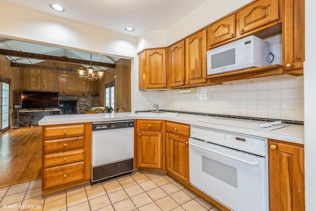 9445 Le Claire Ave, Skokie, IL 60077 - kitchen with white appliances, brown cabinetry, a peninsula, a chandelier, and wooden walls