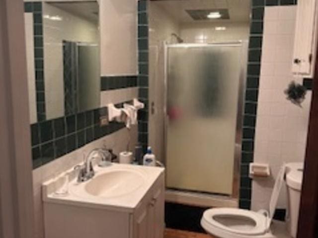 bathroom featuring tile walls, vanity, and a stall shower