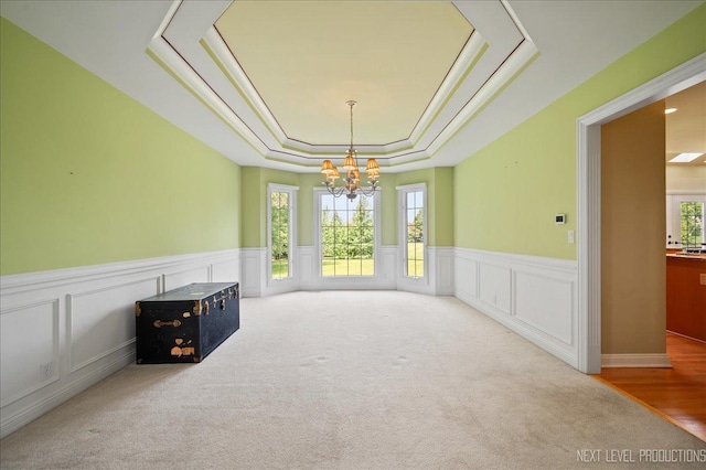 36W850 Red Gate Ct, Saint Charles, IL 60175 - unfurnished living room with a tray ceiling, a chandelier, carpet, wainscoting, and a decorative wall