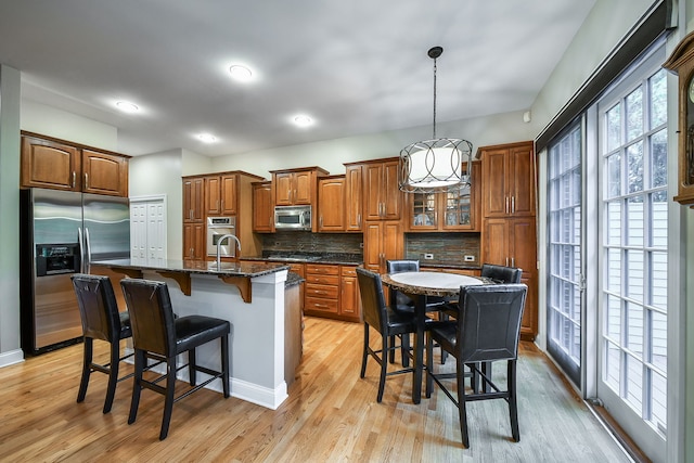 17 Virginia Pkwy, Schaumburg, IL 60193 - kitchen with appliances with stainless steel finishes, brown cabinets, a breakfast bar area, tasteful backsplash, and light wood-style flooring