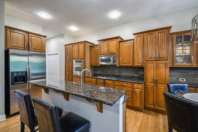 17 Virginia Pkwy, Schaumburg, IL 60193 - kitchen with stainless steel appliances, brown cabinetry, a kitchen bar, backsplash, and light wood finished floors