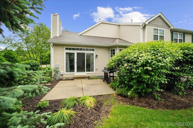 211 Trentt Dr Unit 211, Batavia, IL 60510 - rear view of property featuring a chimney, a patio area, and roof with shingles