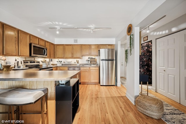 5854 N Kenmore Ave Unit 4F, Chicago, IL 60660 - kitchen with stainless steel appliances, light wood finished floors, rail lighting, and a peninsula