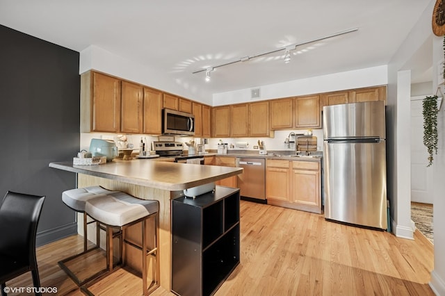 5854 N Kenmore Ave Unit 4F, Chicago, IL 60660 - kitchen with appliances with stainless steel finishes, a peninsula, light wood-type flooring, and a breakfast bar