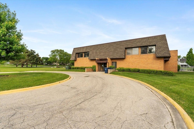 1300 Woodside Ct Unit B2, Schaumburg, IL 60193 - view of front of home featuring roof with shingles, brick siding, a front yard, and curved driveway