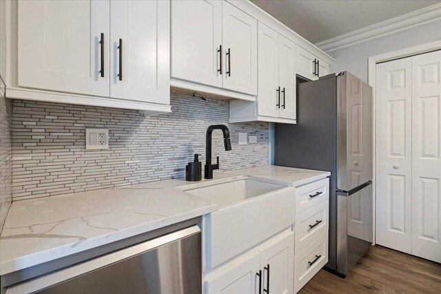 1300 Woodside Ct Unit B2, Schaumburg, IL 60193 - kitchen featuring a sink, crown molding, appliances with stainless steel finishes, backsplash, and white cabinetry