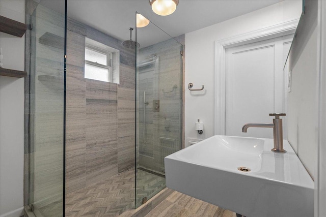2087 W Greenleaf Ave, Chicago, IL 60645 - bathroom featuring a stall shower, a sink, and wood finished floors