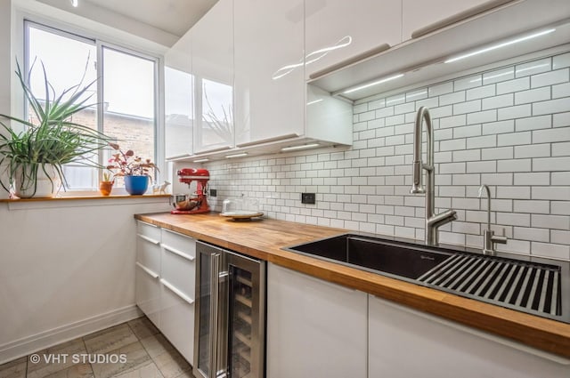 932 W Sunnyside Ave Unit 3C, Chicago, IL 60640 - kitchen featuring beverage cooler, wood counters, a sink, tasteful backsplash, and white cabinetry