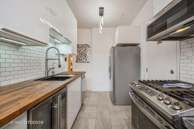 932 W Sunnyside Ave Unit 3C, Chicago, IL 60640 - kitchen with wood counters, appliances with stainless steel finishes, a sink, wine cooler, and white cabinets