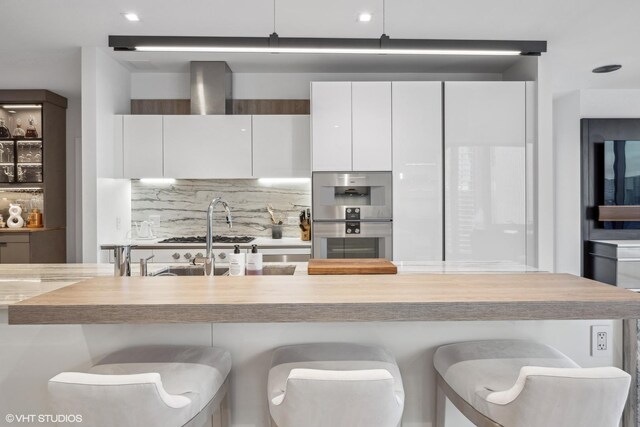 363 E Wacker Dr Unit 3703, Chicago, IL 60601 - kitchen featuring double oven, decorative backsplash, a kitchen breakfast bar, and white cabinets