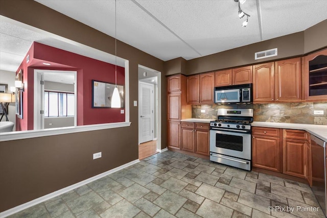 1327 Brown St Unit 206, Des Plaines, IL 60016 - kitchen featuring appliances with stainless steel finishes, baseboards, tasteful backsplash, brown cabinetry, and a textured ceiling