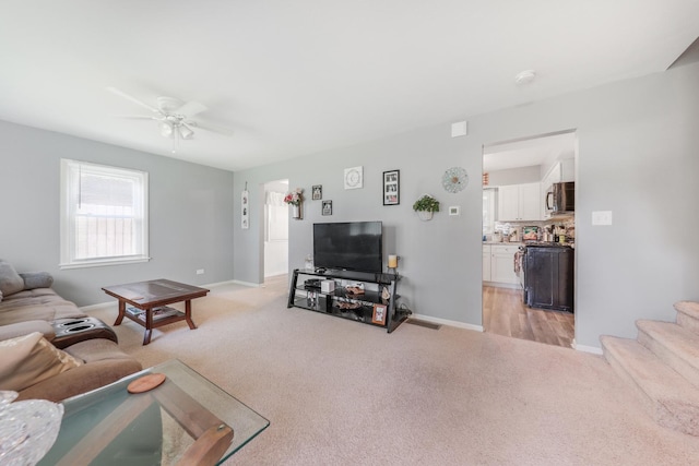 201 N First St, Wilmington, IL 60481 - living area featuring light colored carpet, a ceiling fan, baseboards, and stairs