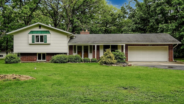 split level home with a garage, brick siding, driveway, a front yard, and a chimney