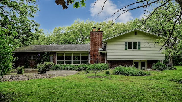rear view of house with a yard, a chimney, and brick siding