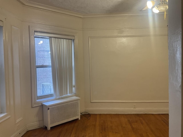 6832 S S Shore Dr Unit 1, Chicago, IL 60649 - empty room featuring radiator heating unit, ornamental molding, wood finished floors, and a textured ceiling