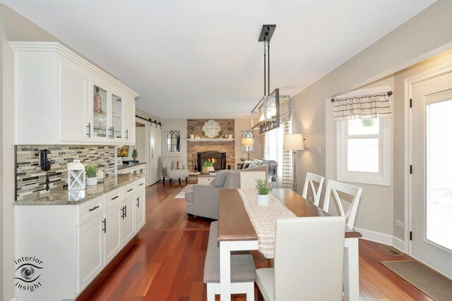883 White Tail Bnd, Manteno, IL 60950 - dining room featuring dark wood-style floors, plenty of natural light, a stone fireplace, and baseboards