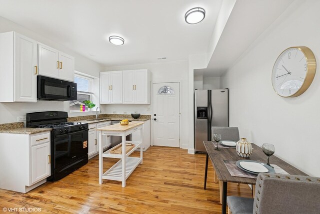 3849 W Ainslie St Unit 1, Chicago, IL 60625 - kitchen featuring black appliances, a sink, white cabinetry, light wood-type flooring, and light stone counters