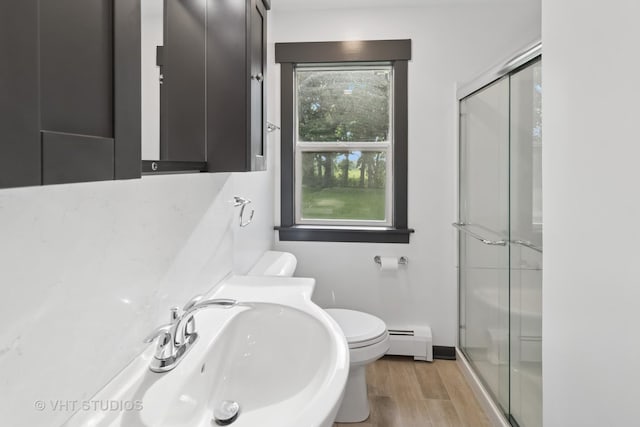 2309 N Riverside Dr, Mchenry, IL 60051 - bathroom with a baseboard radiator, a sink, a shower stall, toilet, and wood finished floors