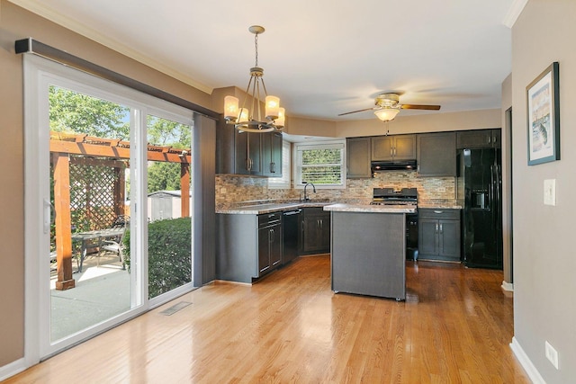 325 Indian Ridge Trl, Wauconda, IL 60084 - kitchen with black appliances, under cabinet range hood, decorative backsplash, a chandelier, and light wood-style flooring