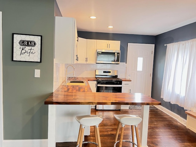 1474 Forest Ave, Calumet City, IL 60409 - kitchen featuring wooden counters, appliances with stainless steel finishes, a sink, tasteful backsplash, and baseboards