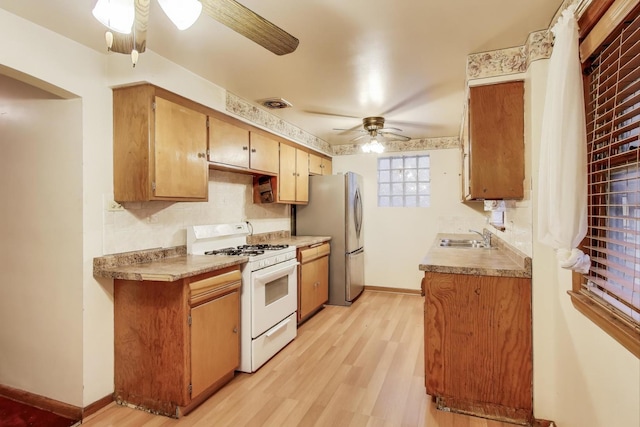 6636 S Rockwell St, Chicago, IL 60629 - kitchen with white gas stove, ceiling fan, a sink, light wood finished floors, and freestanding refrigerator
