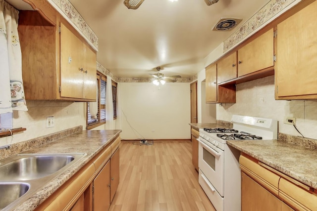 6636 S Rockwell St, Chicago, IL 60629 - kitchen with white gas range oven, backsplash, a sink, and light wood-style floors