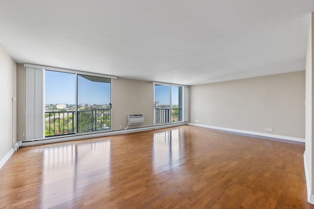 40 N Tower Rd Unit 14B, Oak Brook, IL 60523 - spare room featuring a wall mounted AC, baseboards, wood finished floors, and a wall of windows