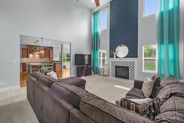 679 Slate Run, Elgin, IL 60124 - living room featuring a high ceiling, a ceiling fan, a tiled fireplace, light colored carpet, and baseboards