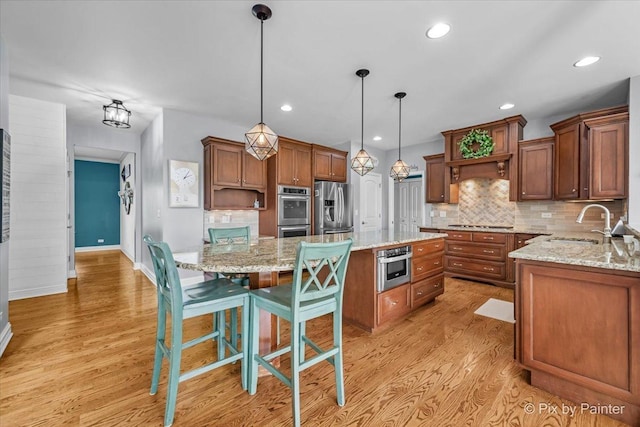 679 Slate Run, Elgin, IL 60124 - kitchen with stainless steel appliances, a center island, a sink, light wood-style flooring, and backsplash