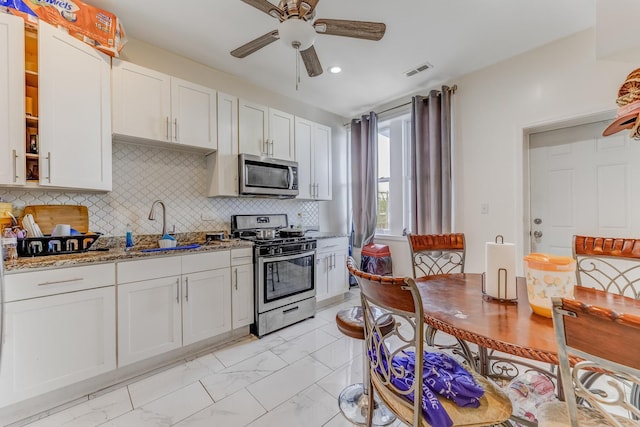 3340 W Polk St, Chicago, IL 60624 - kitchen featuring stainless steel appliances, a sink, light marble finish flooring, light stone counters, and a ceiling fan