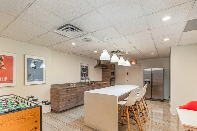 1221 N Dearborn St Unit 207N, Chicago, IL 60610 - kitchen featuring appliances with stainless steel finishes, wall chimney range hood, a breakfast bar, a center island, and a sink